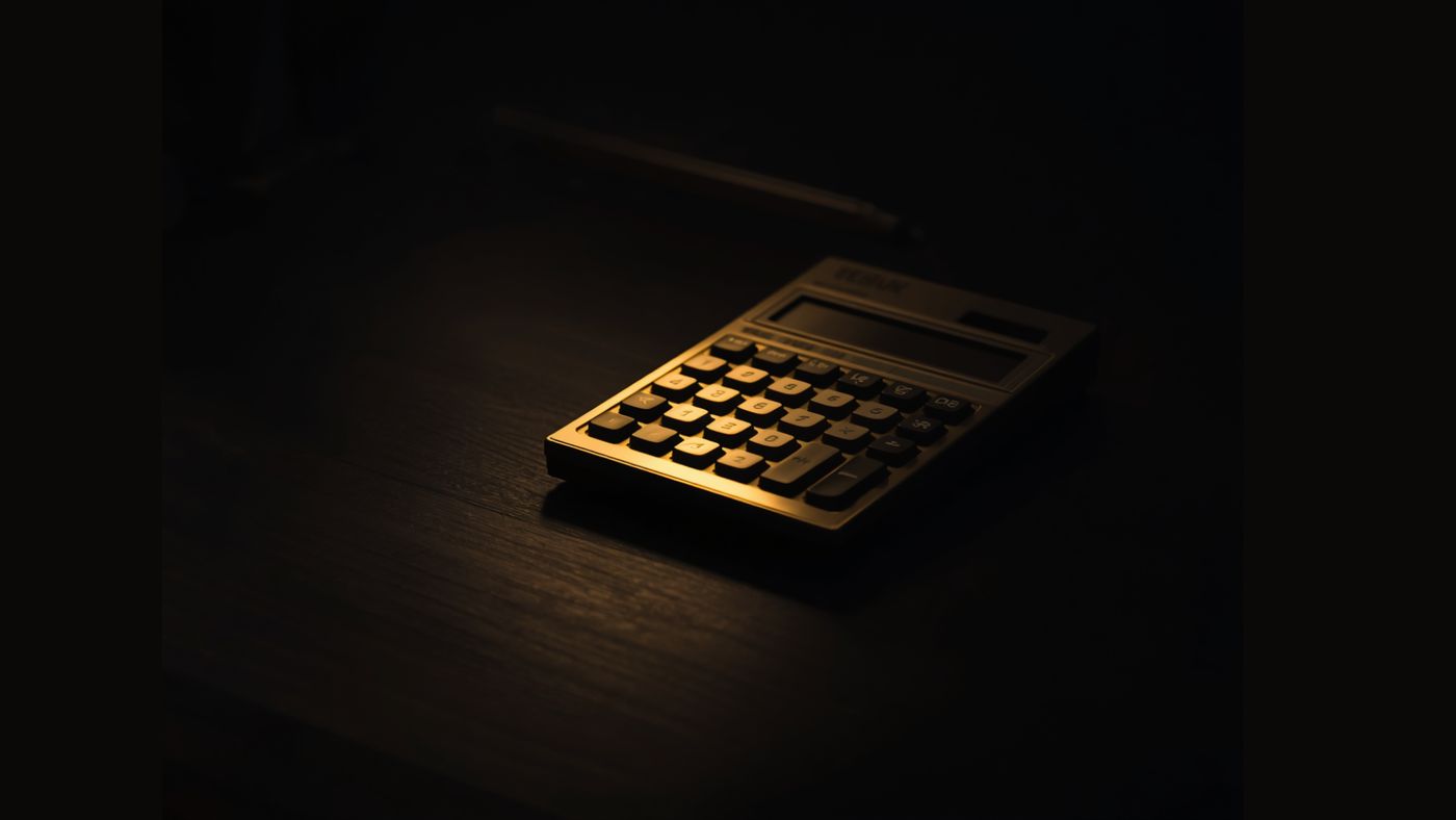 A gold calculator lit on a dark desk.